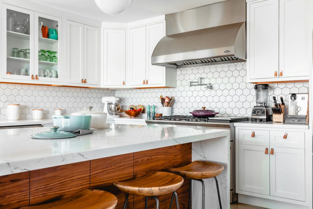 Kitchen with white quartz countertop and porcelain hexagon white tiles.